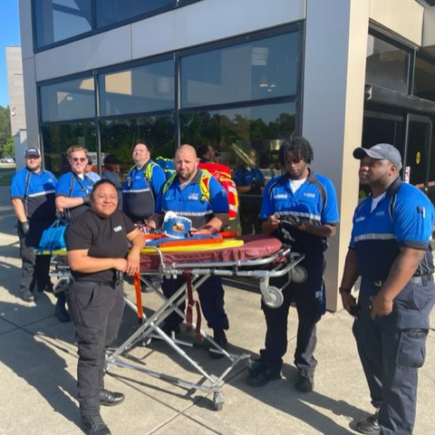 EMT apprentices in uniform outside of a building around a stretcher